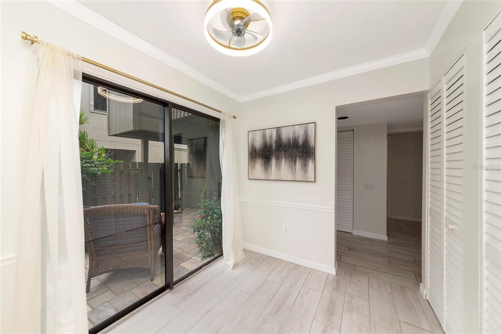 A dining area features light wood-look tile floors, a ceiling fan, and sliding glass patio doors — 108 WOODLAND PLACE UNIT 108, OSPREY, FL