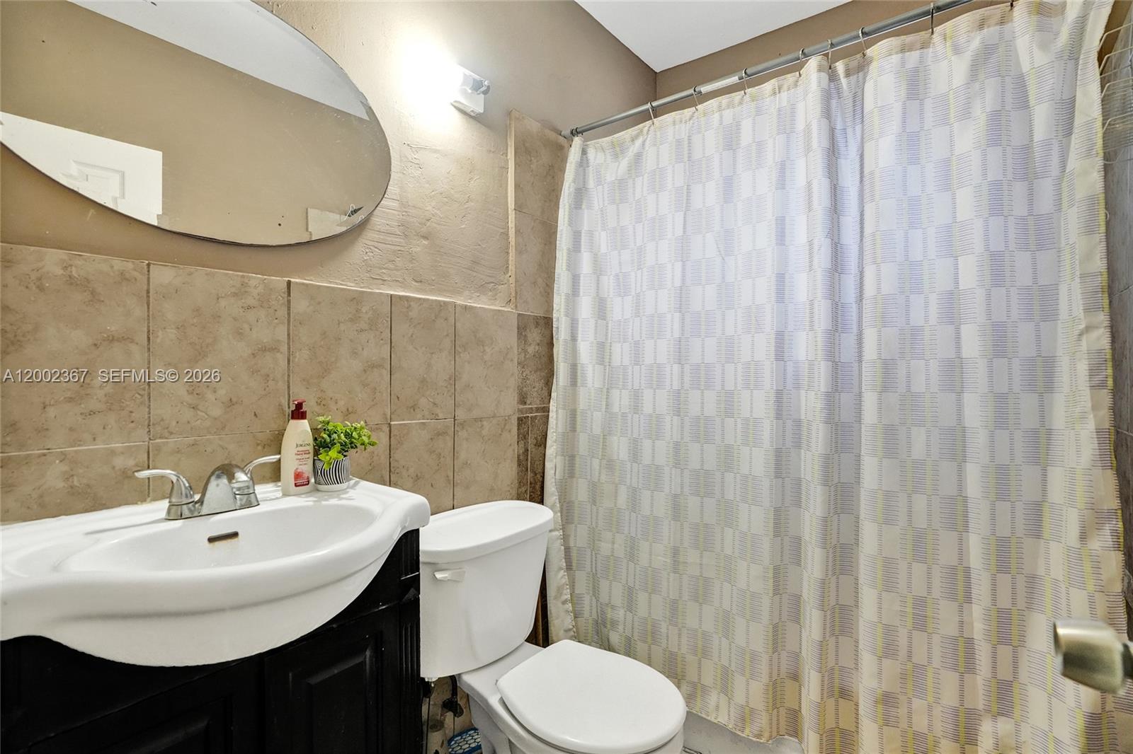 A bathroom features a vanity with a white sink, a toilet, and a shower curtain — 836 NW 101st St, Miami FL 33150, MIAMI, FL