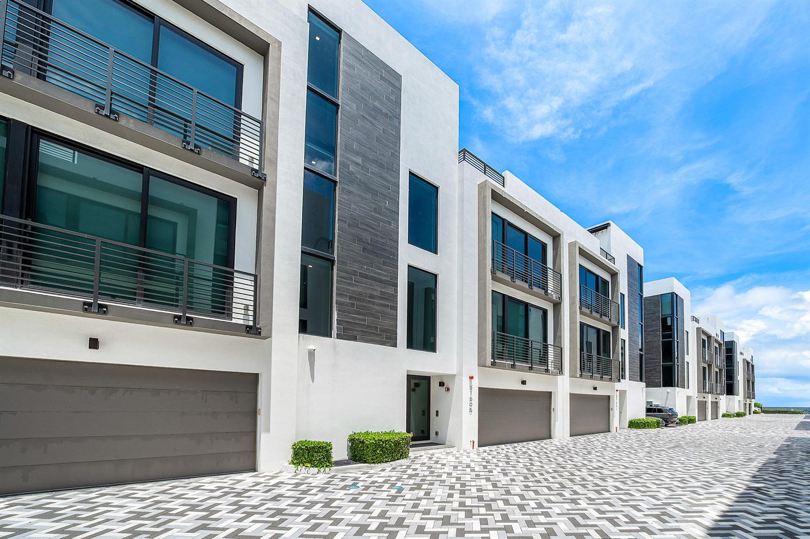 A row of modern three-story townhomes with white stucco, dark tile accents, and paved driveways — 11505 Old Ocean Boulevard, Ocean Ridge FL 33435, OCEAN RIDGE, FL