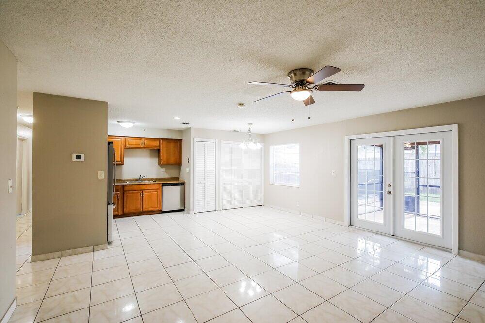 A kitchen with wood cabinets and tile flooring opens into a bright dining area — CORAL SPRINGS, FL