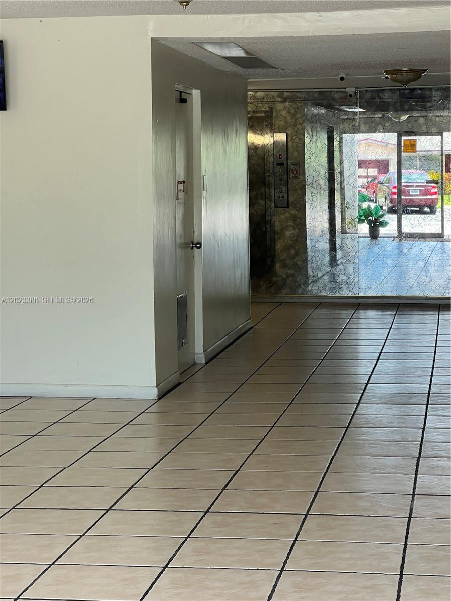 A tiled lobby features a plain wall, a closed door, and a glass-paneled entrance — 2060 NW 48th Ter # 103, Lauderhill FL 33313, LAUDERHILL, FL