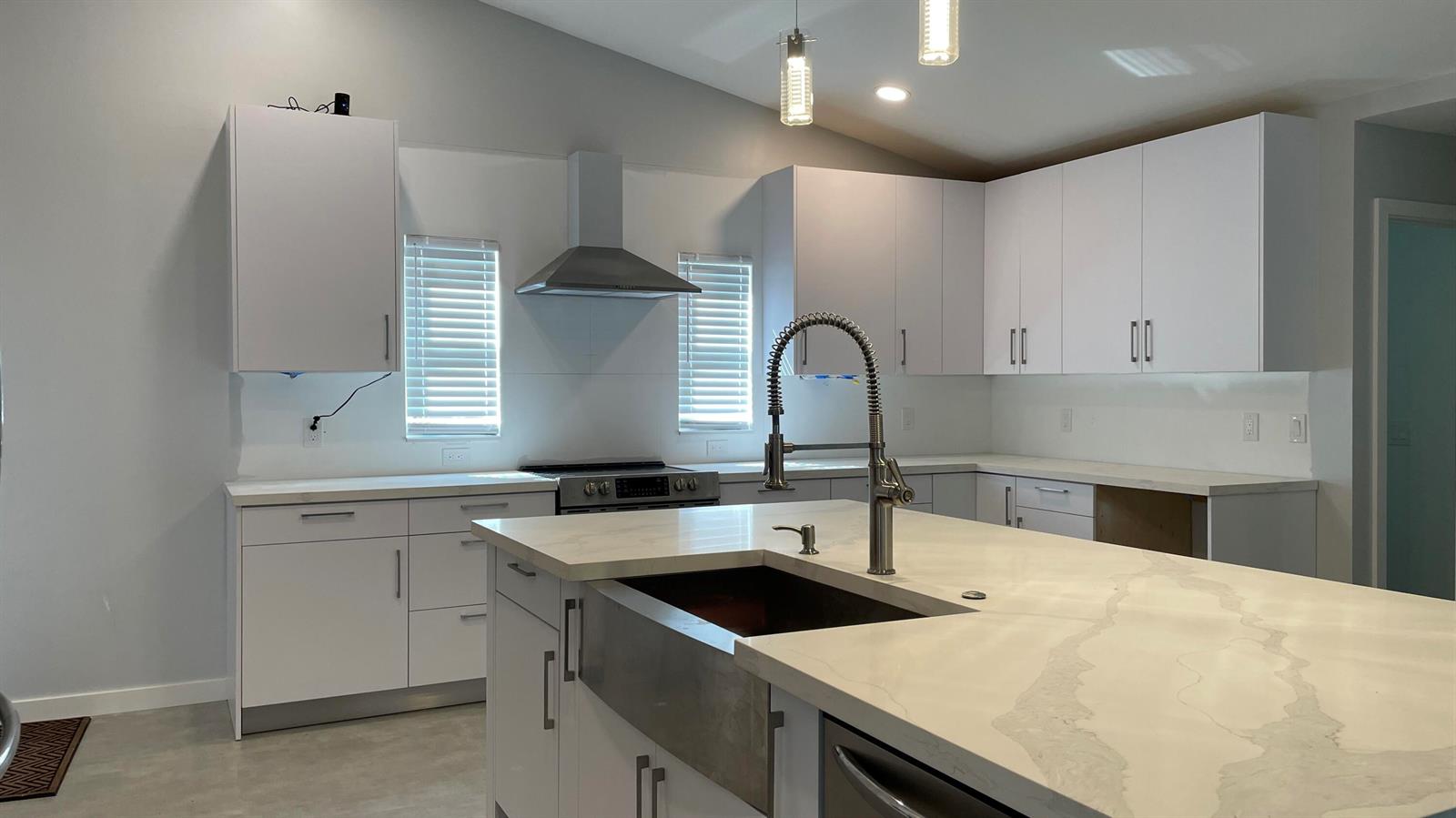 A modern kitchen features white cabinets, quartz countertops, a farmhouse sink, and stainless steel appliances — 17548 32nd Lane N, FL 33470, FL