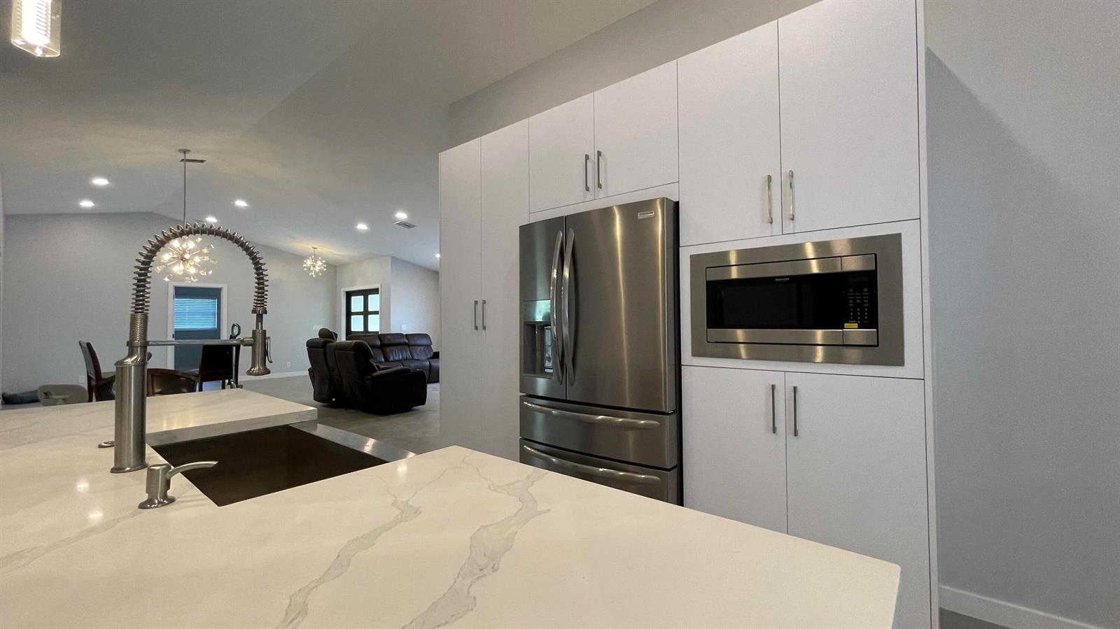 A modern kitchen features white cabinetry, stainless steel appliances, and a marble-patterned island countertop — 17548 32nd Lane N, FL 33470, FL