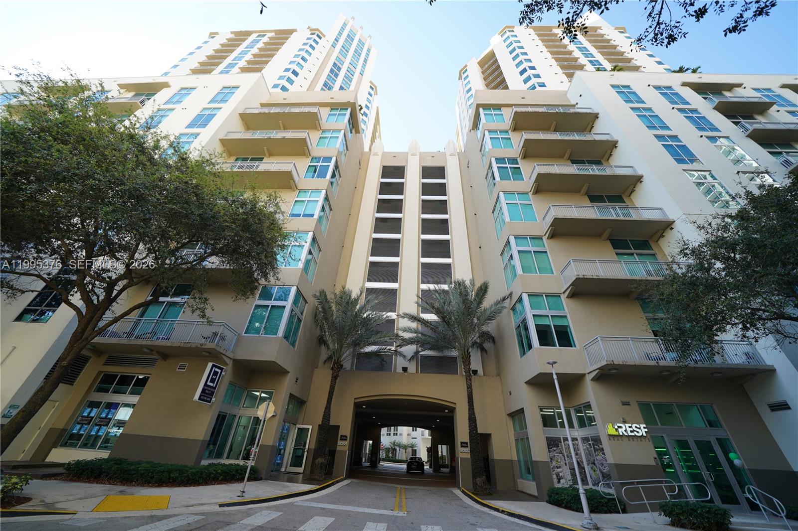 A low-angle view of a multi-story apartment building with a central driveway entrance — 9066 SW 73rd Ct # 1701, Miami FL 33156, MIAMI, FL