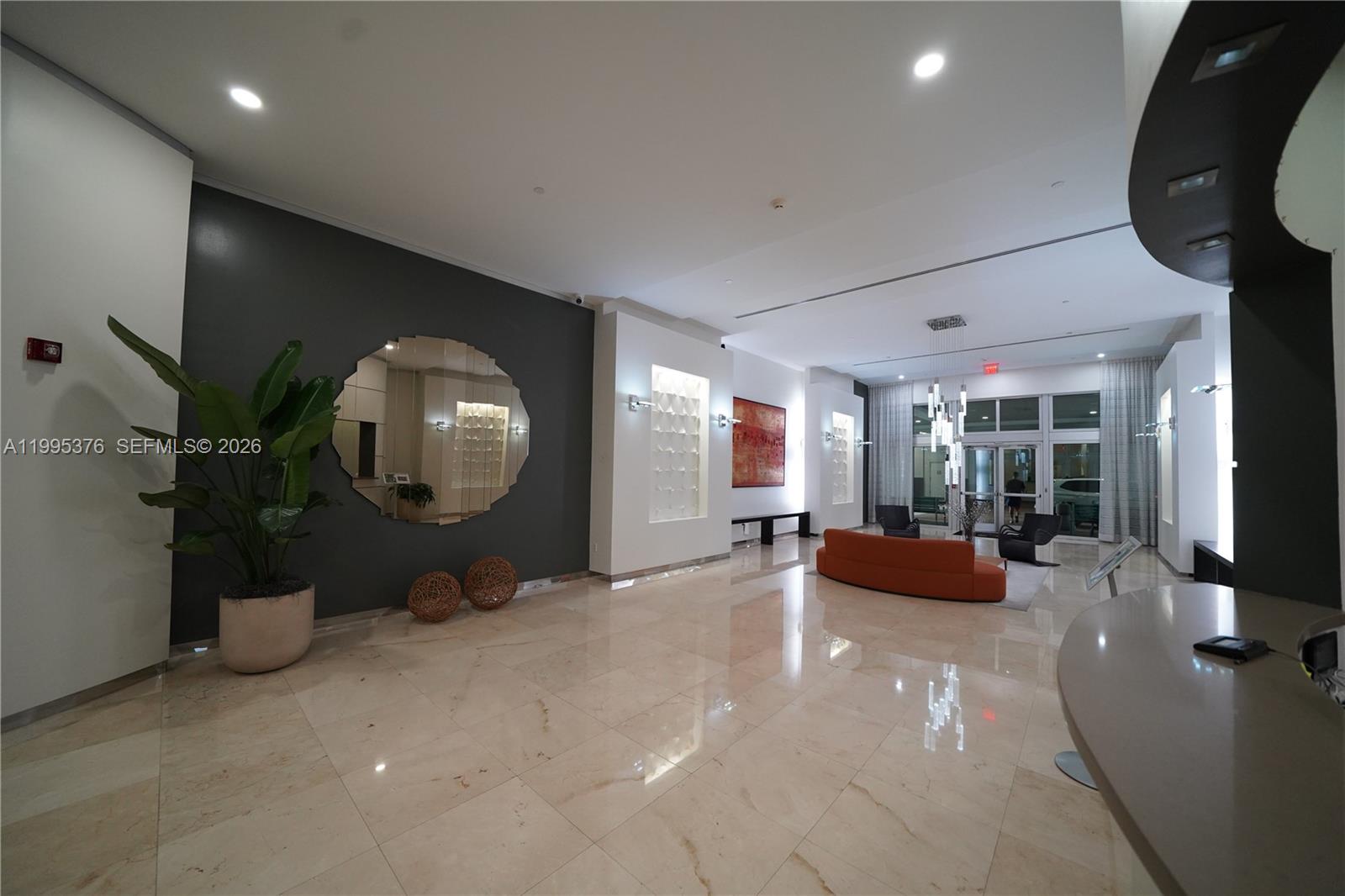 A modern building lobby features a dark accent wall, a circular mirror, and marble flooring — 9066 SW 73rd Ct # 1701, Miami FL 33156, MIAMI, FL
