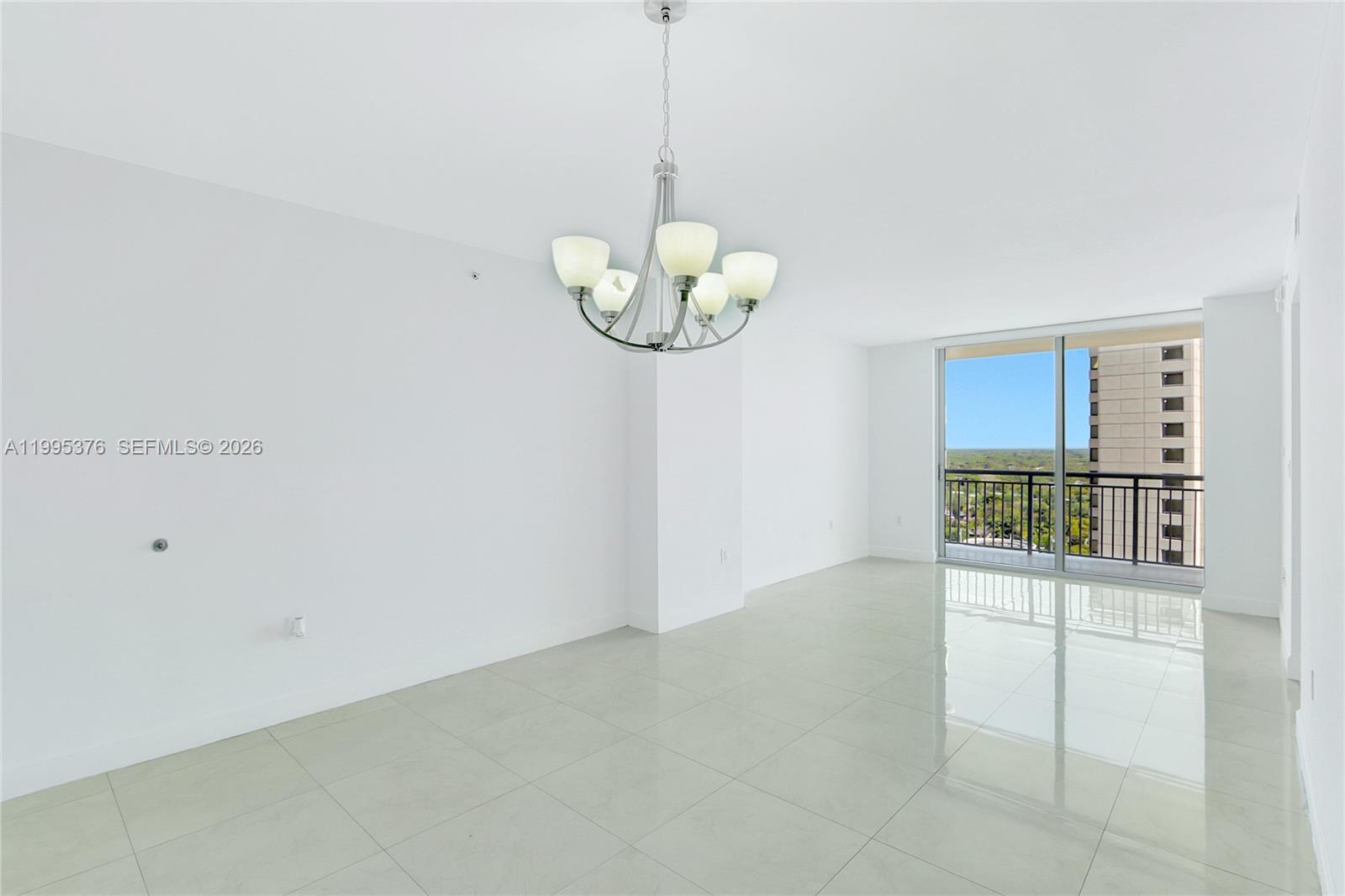 A bright, empty room features white walls, polished tile flooring, and a modern chandelier — 9066 SW 73rd Ct # 1701, Miami FL 33156, MIAMI, FL