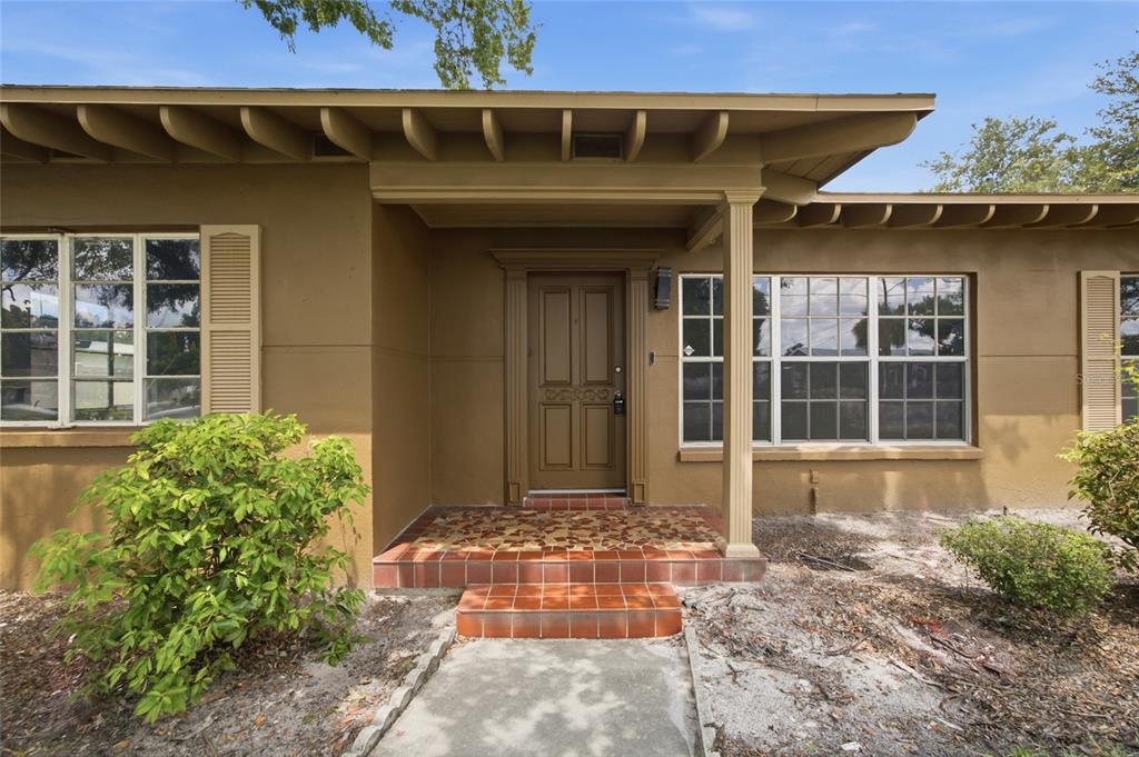 A brown house exterior features a covered entryway with tiled steps and a front door — 808 N MACDILL AVENUE, TAMPA, FL