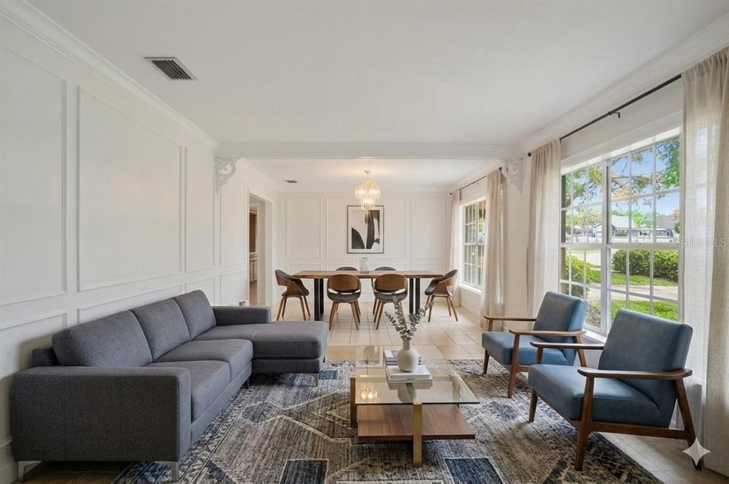 A living and dining room with white paneled walls, a gray sectional, and blue chairs — 808 N MACDILL AVENUE, TAMPA, FL