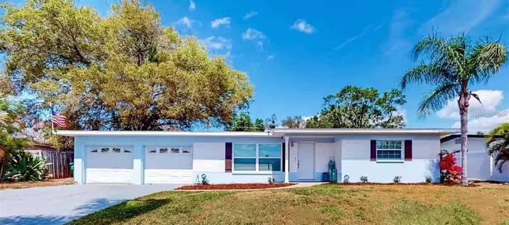 A single-story house with a light blue exterior, two garage doors, and a palm tree — 2760 KUMQUAT DRIVE UNIT 001, CLEARWATER, FL