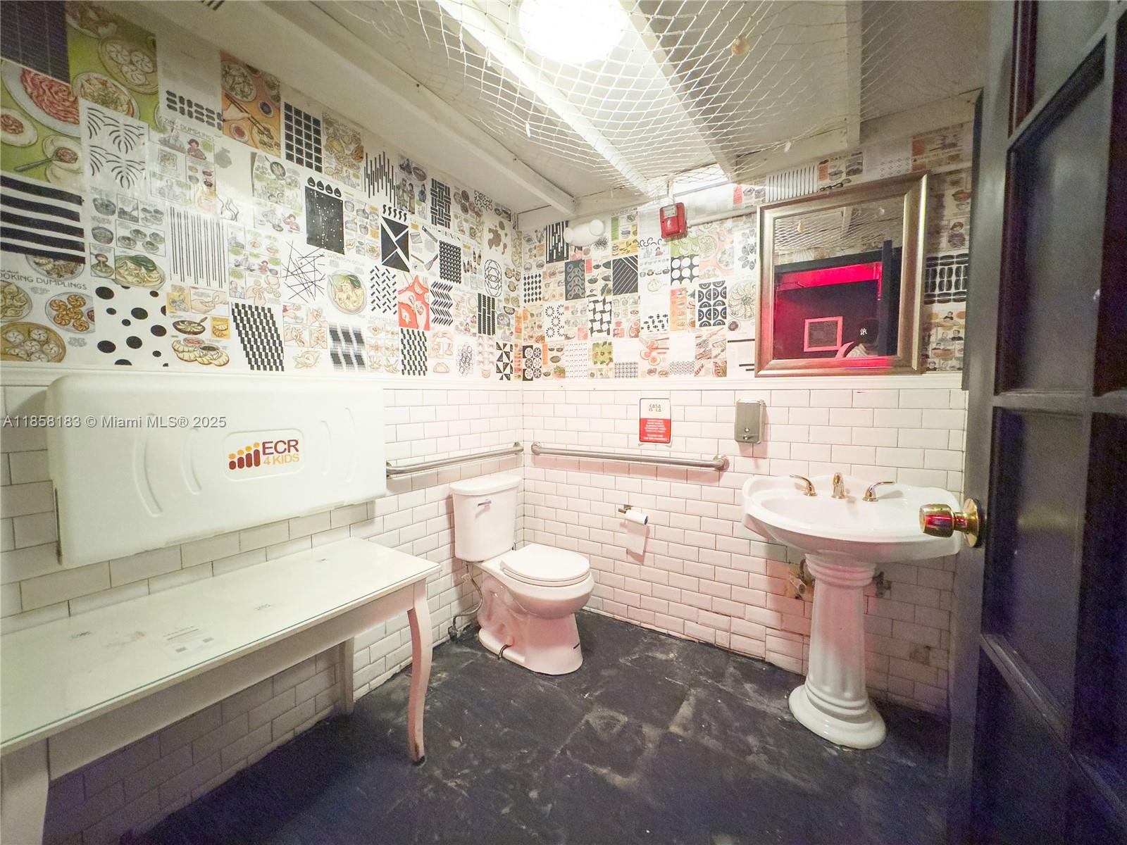 A bathroom features a patterned wallpaper, white subway tiles, a pedestal sink, and a toilet — 1410 20th St # 1418, Miami Beach FL 33139, MIAMI BEACH, FL