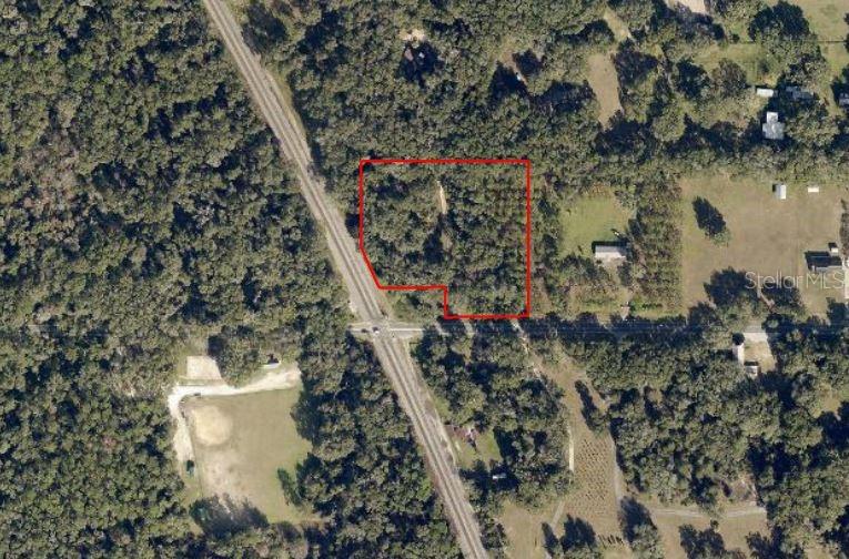 A gravel driveway leads from a paved road into a wooded, undeveloped residential lot — SE 80TH STREET STREET SE, OCALA, FL