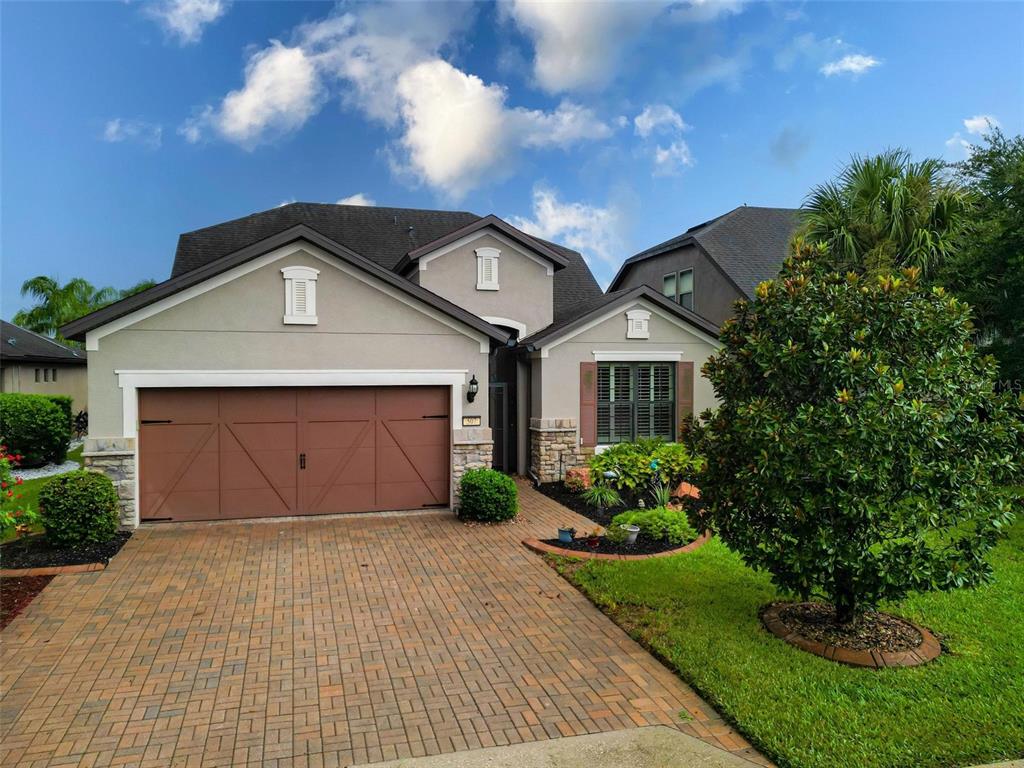 A single-story house with a brown garage door, stone accents, and a brick paver driveway — 507 CADIZ DRIVE, DAVENPORT, FL