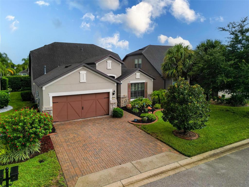 A two-story suburban house features a brick paver driveway, a two-car garage, and landscaping — 507 CADIZ DRIVE, DAVENPORT, FL
