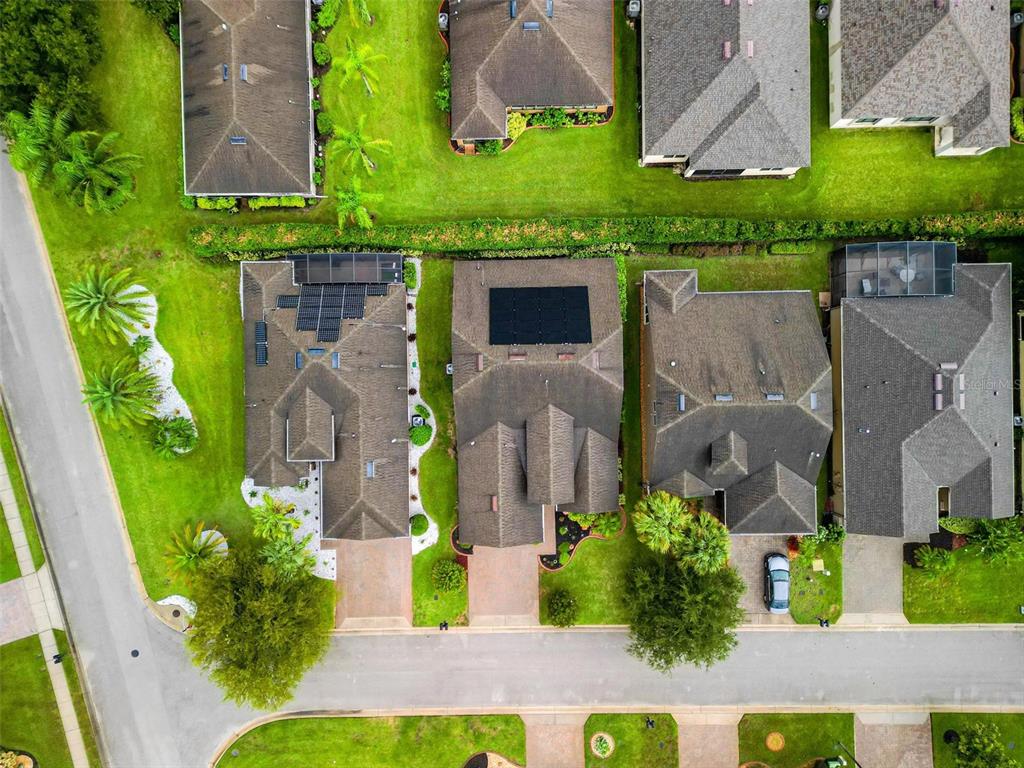 An aerial view shows several suburban houses with shingled roofs, solar panels, and green lawns — 507 CADIZ DRIVE, DAVENPORT, FL