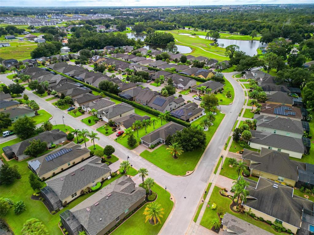 An aerial view shows a suburban neighborhood with single-family homes, manicured lawns, and a pond — 507 CADIZ DRIVE, DAVENPORT, FL