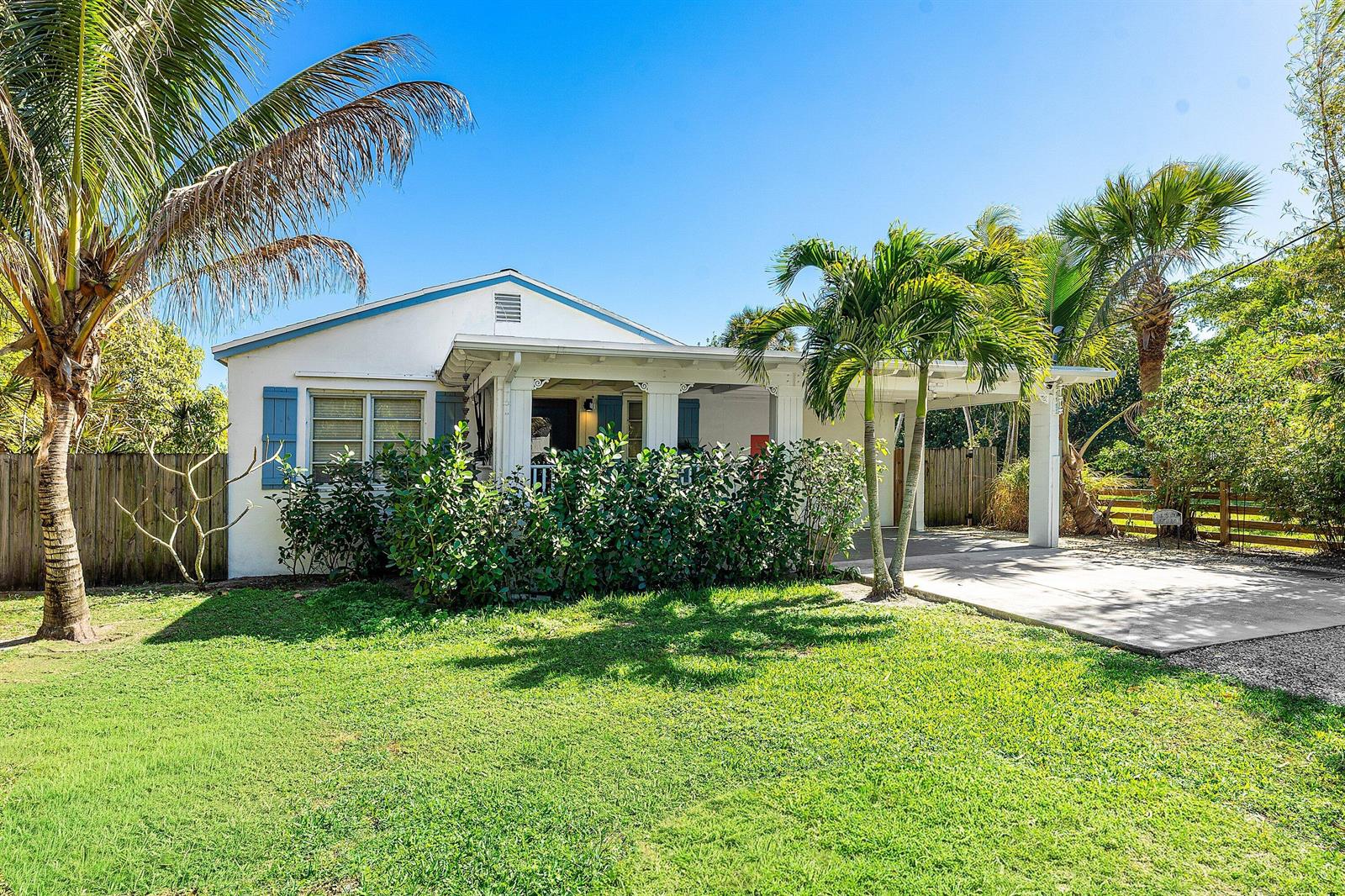 A white single-story house with a front porch, carport, and palm trees in the yard — 110 Wilson Road, West Palm Beach FL 33406, WEST PALM BEACH, FL