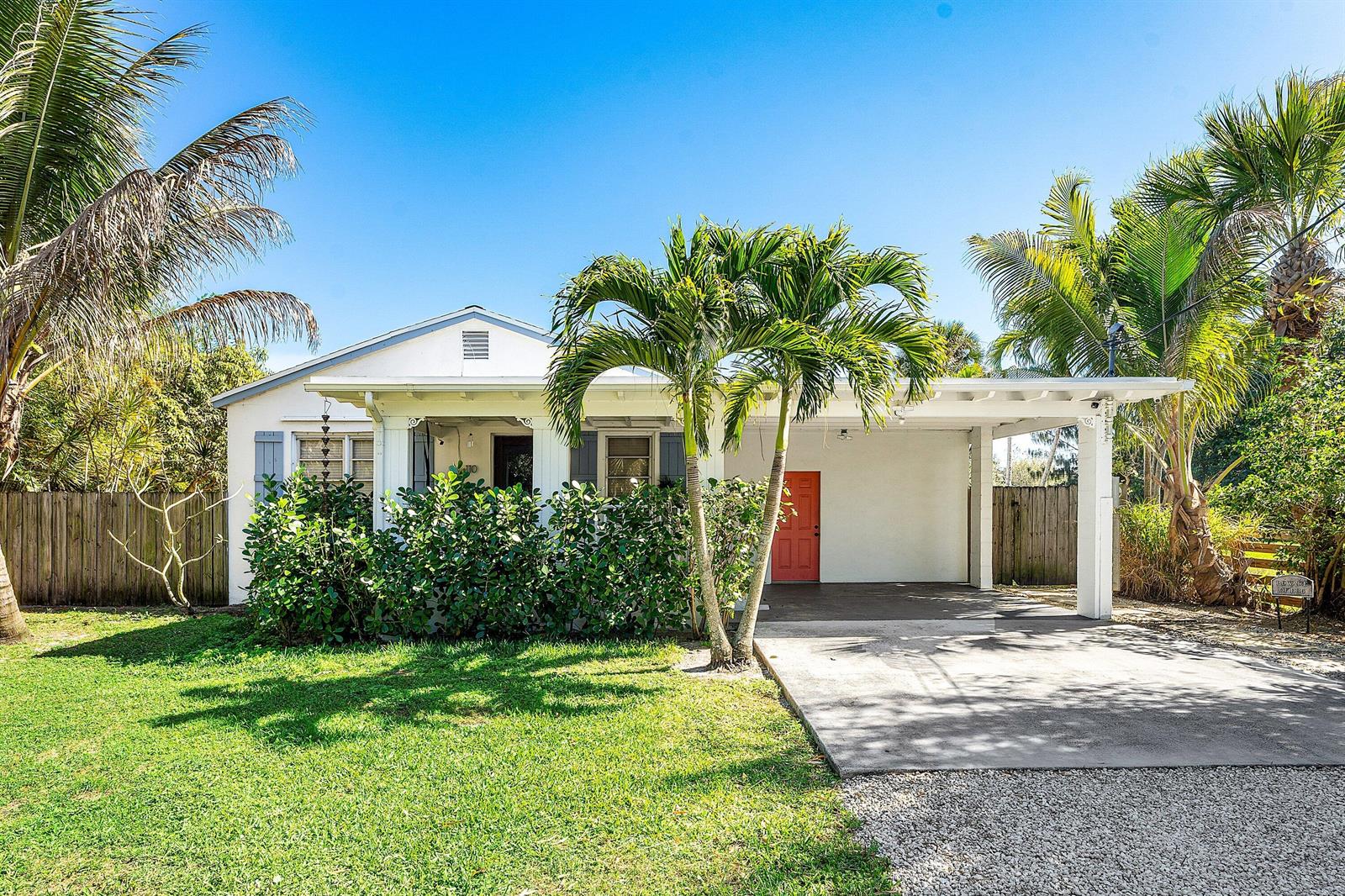 A single-story house with a white exterior, a carport, and a bright orange front door — 110 Wilson Road, West Palm Beach FL 33406, WEST PALM BEACH, FL