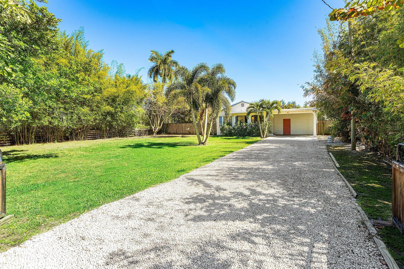 A gravel driveway leads to a single-story house with a lawn and palm trees — 110 Wilson Road, West Palm Beach FL 33406, WEST PALM BEACH, FL
