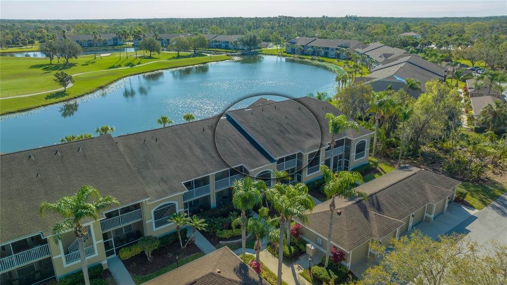 An aerial view of a multi-story apartment building with a dark shingled roof and lake — 5241 MAHOGANY RUN AVENUE UNIT 425, SARASOTA, FL