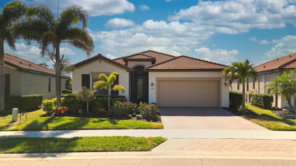 A single-story house with a tiled roof, a two-car garage, and a landscaped front yard — 10475 MEDJOOL DRIVE, VENICE, FL
