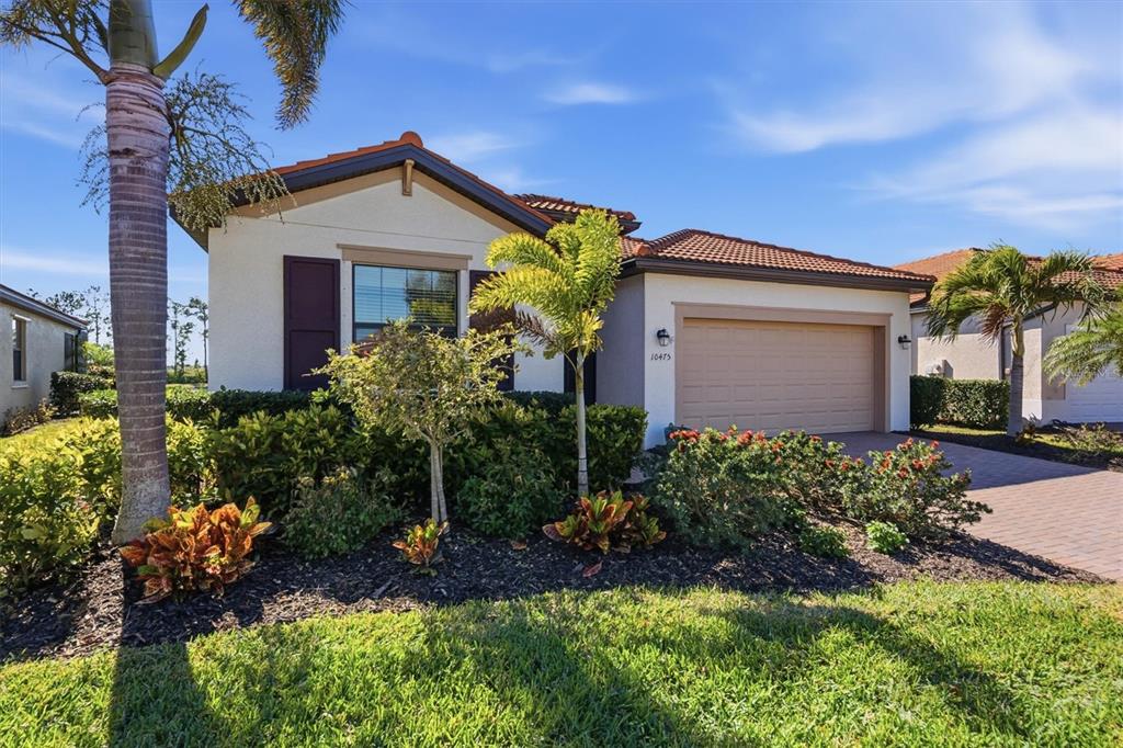 A single-story house with a tan garage, tile roof, and palm trees in the front yard — 10475 MEDJOOL DRIVE, VENICE, FL