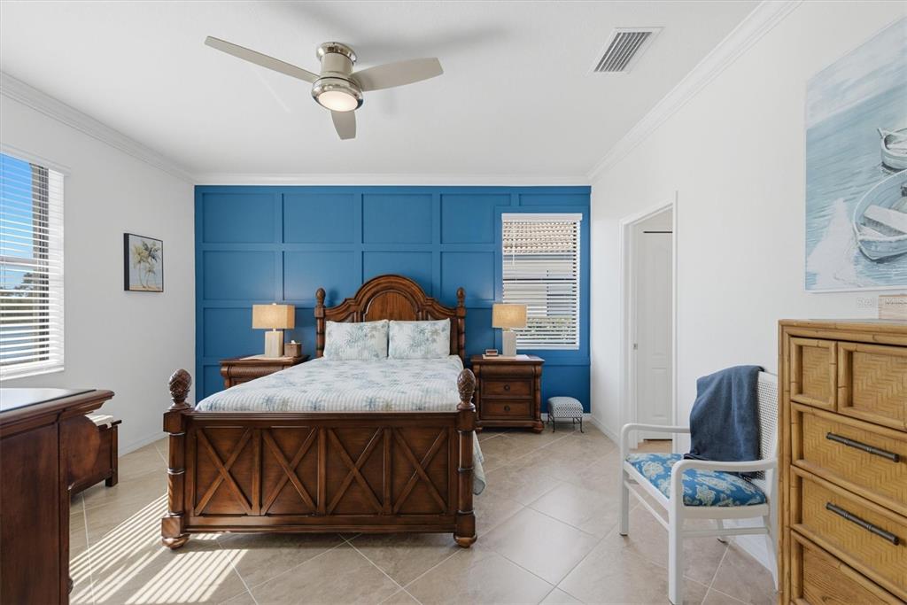 A bedroom features a blue paneled accent wall, a wooden bed frame, and tile flooring — 10475 MEDJOOL DRIVE, VENICE, FL