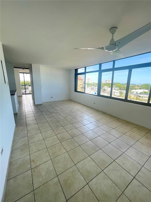 An empty room features light-colored tile flooring, a ceiling fan, and large windows with views — 1 INGA STREET UNIT 6H, SAN JUAN, PR