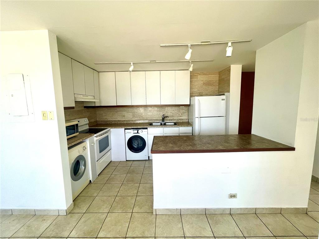A kitchen features white cabinets, a dark countertop, tile flooring, and a built-in washing machine — 1 INGA STREET UNIT 6H, SAN JUAN, PR