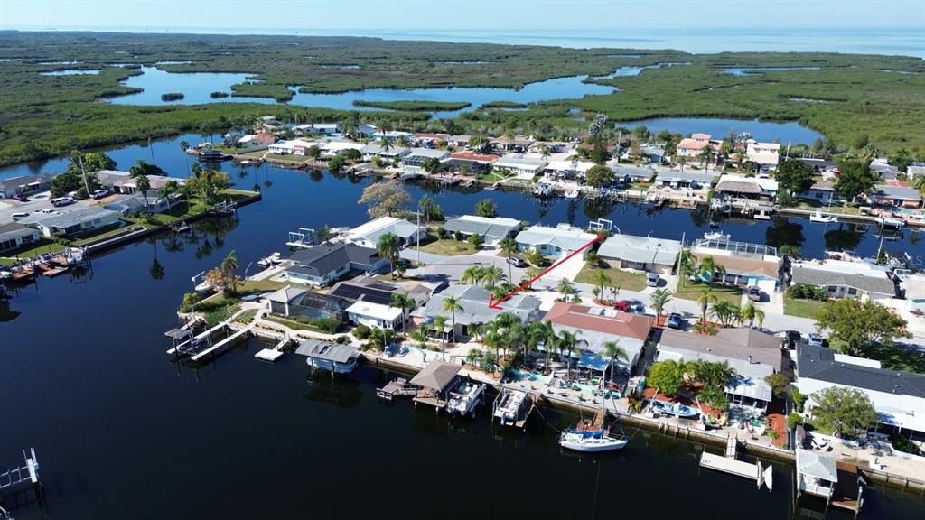 An aerial view of a waterfront home with a boat dock, lift, and covered patio — 12612 4TH ISLE, HUDSON, FL