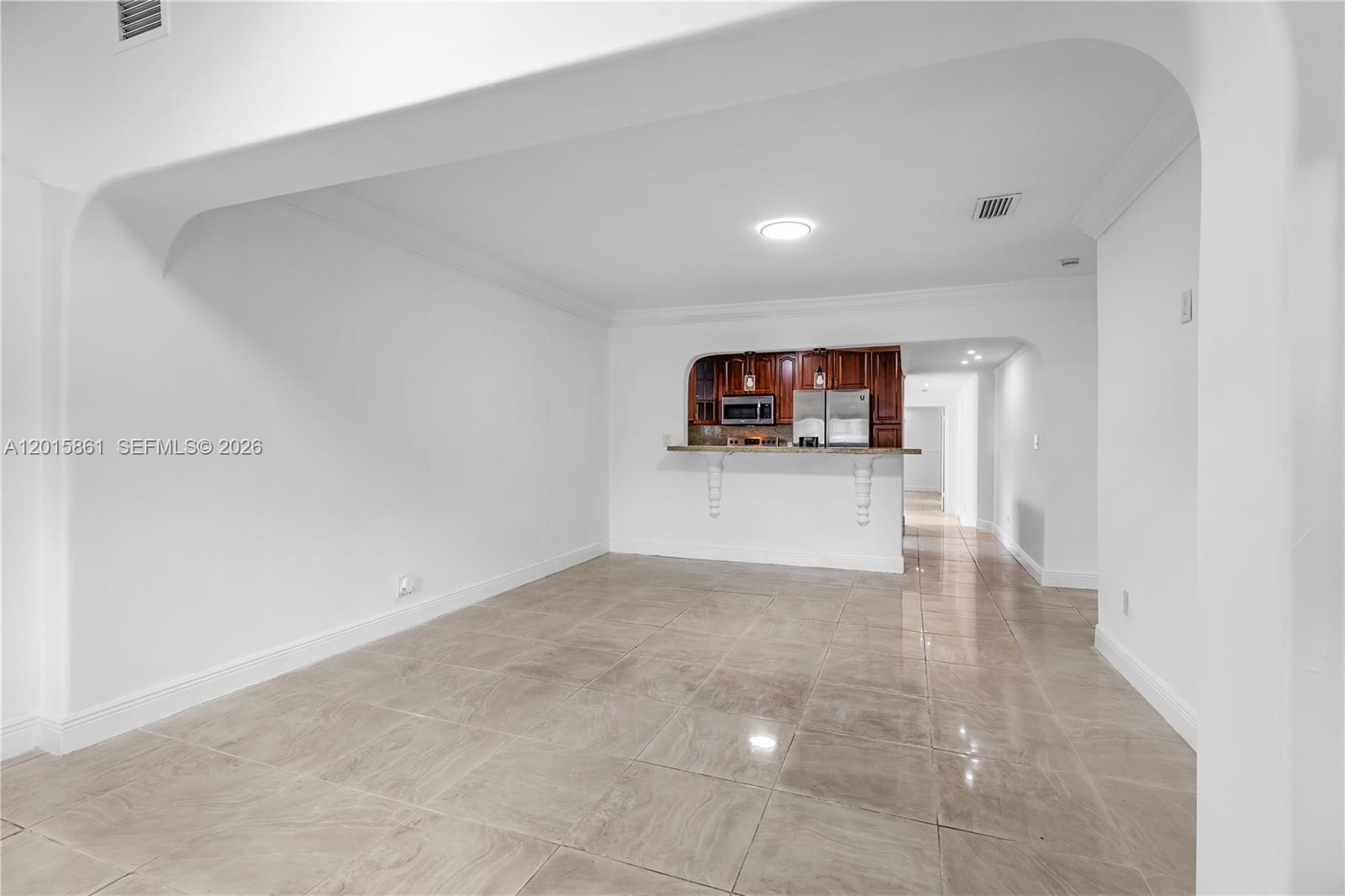An open living area features large beige floor tiles and a pass-through kitchen counter — 1835 SW 18th St, Miami FL 33145, MIAMI, FL