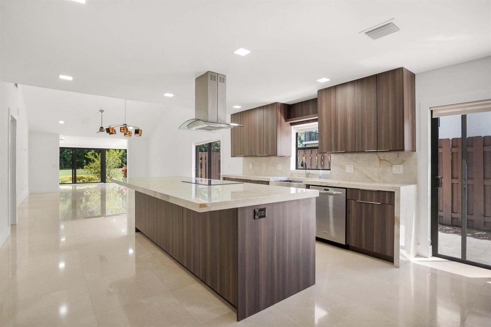 A modern kitchen features dark wood cabinets, a large stone island, and stainless steel appliances — 21922 Cypress Drive # 37b, Boca Raton FL 33433, BOCA RATON, FL