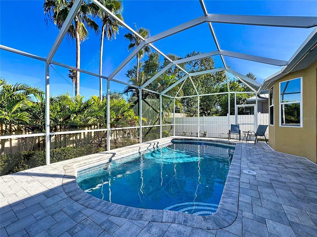 A screened-in patio features a swimming pool surrounded by stone pavers and palm trees — 5376 LEVI LANE, SARASOTA, FL