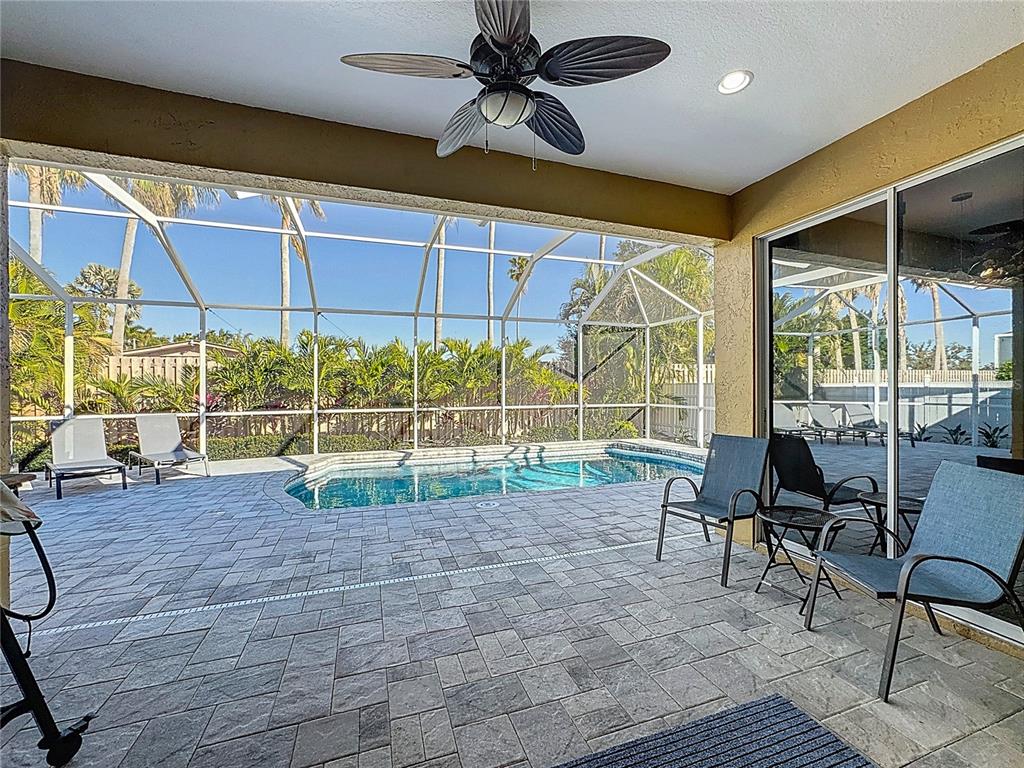 A covered patio with a ceiling fan overlooks a screened-in swimming pool and backyard — 5376 LEVI LANE, SARASOTA, FL