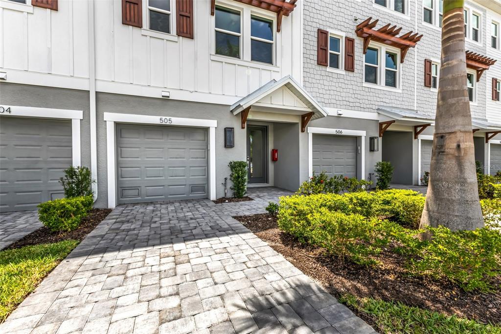 The exterior of two adjacent townhomes features gray garage doors, paved driveways, and landscaping — 1617 SEAHAVEN DRIVE UNIT 505, PUNTA GORDA, FL