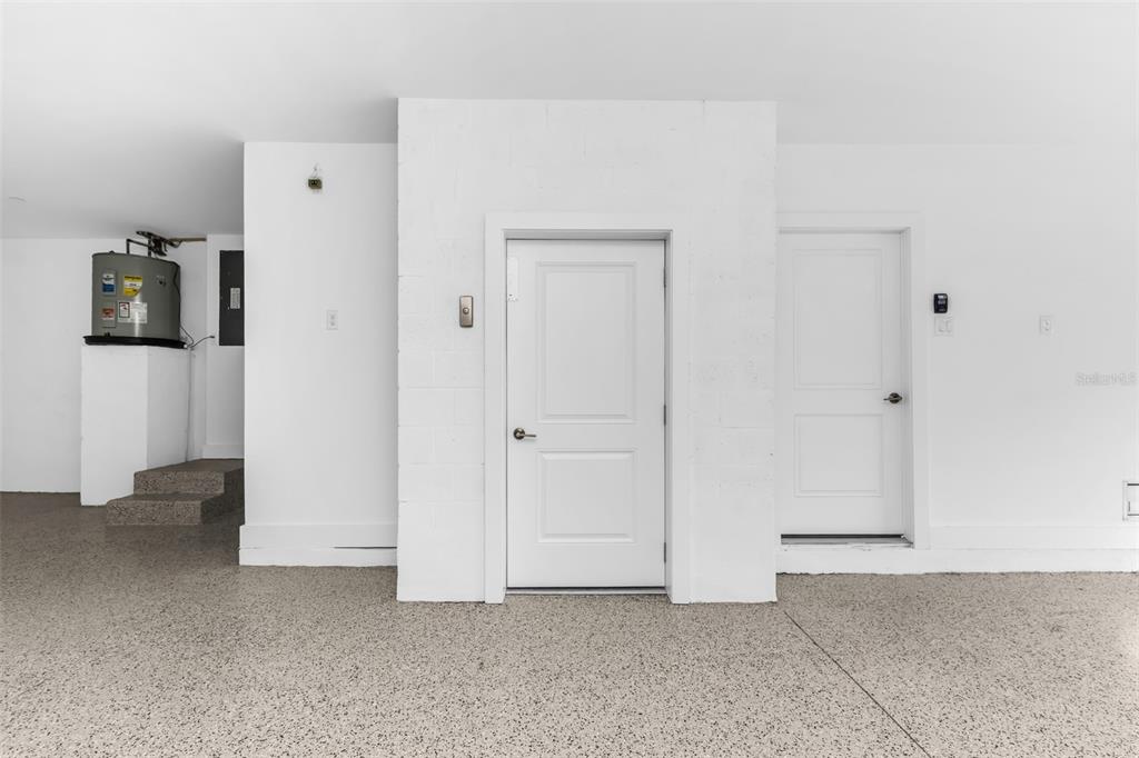 A garage interior features a water heater, two white doors, and speckled epoxy flooring — 1617 SEAHAVEN DRIVE UNIT 505, PUNTA GORDA, FL