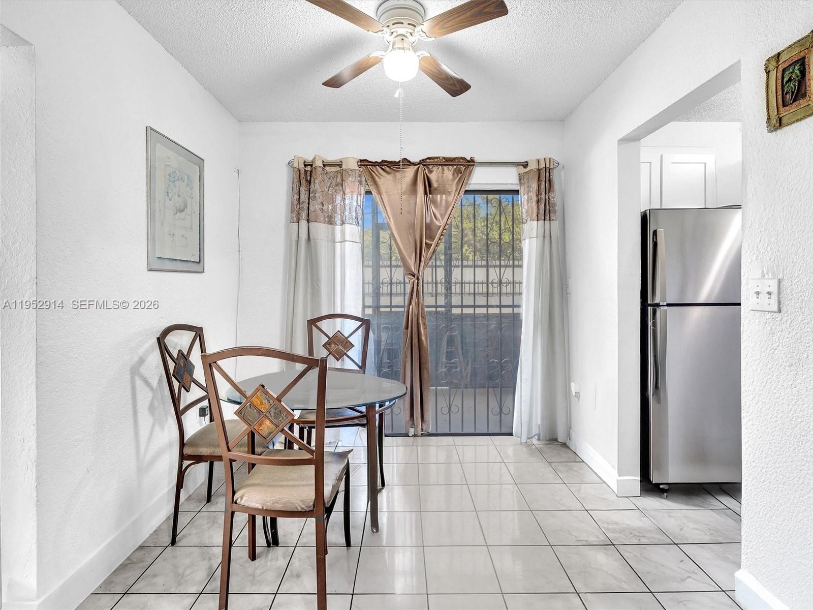 A dining area features a glass-top table, metal chairs, tile flooring, and a sliding glass door — 13500 NE 3rd Ct # 121, North Miami FL 33161, NORTH MIAMI, FL