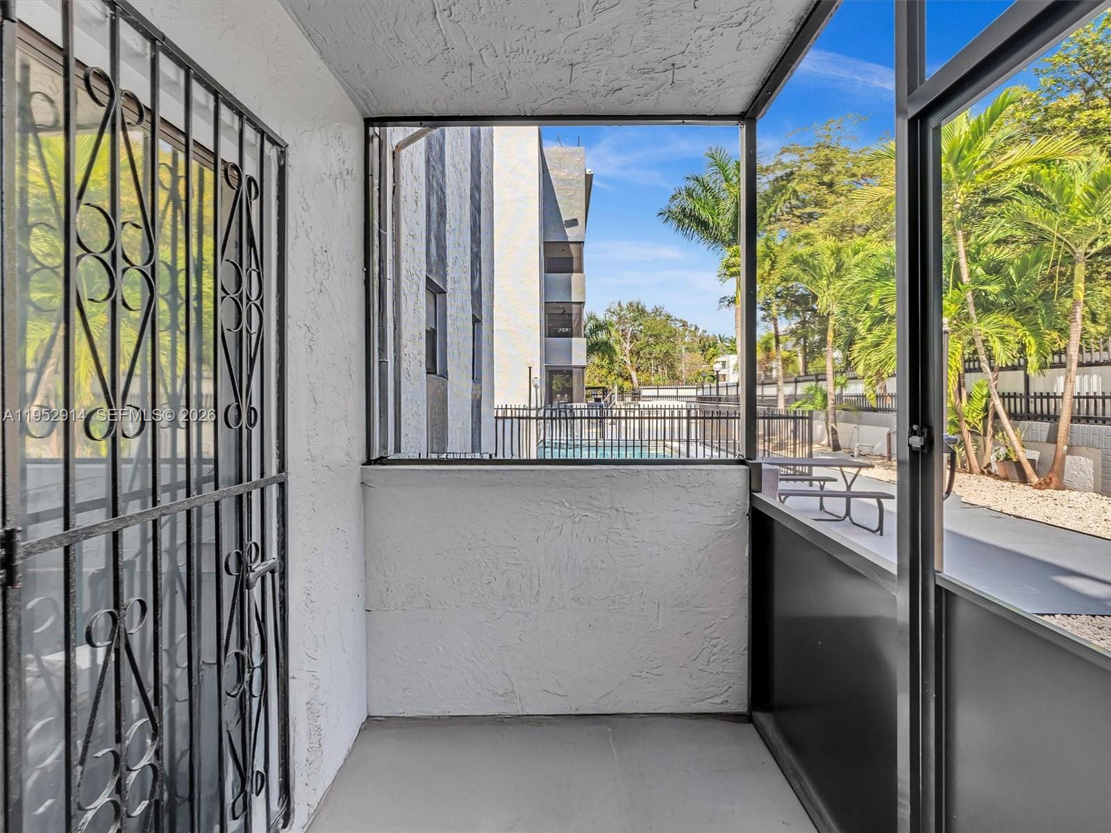 A screened-in balcony features white textured walls, a metal security door, and a pool view — 13500 NE 3rd Ct # 121, North Miami FL 33161, NORTH MIAMI, FL