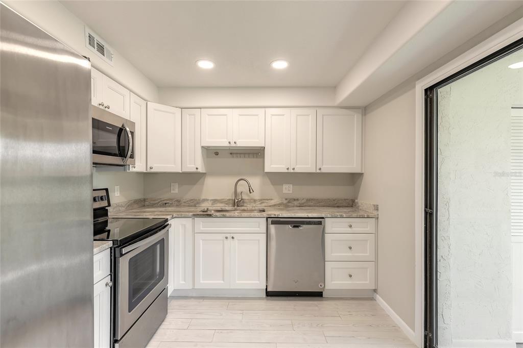A kitchen features white cabinets, stainless steel appliances, and light-colored countertops with a tile floor — 275 INDIGO DRIVE UNIT 204, DAYTONA BEACH, FL
