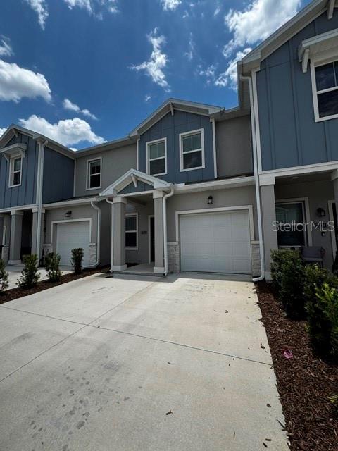 A two-story townhouse exterior features blue siding, a white garage door, and a concrete driveway — 2500 SKYLINE LOOP, KISSIMMEE, FL
