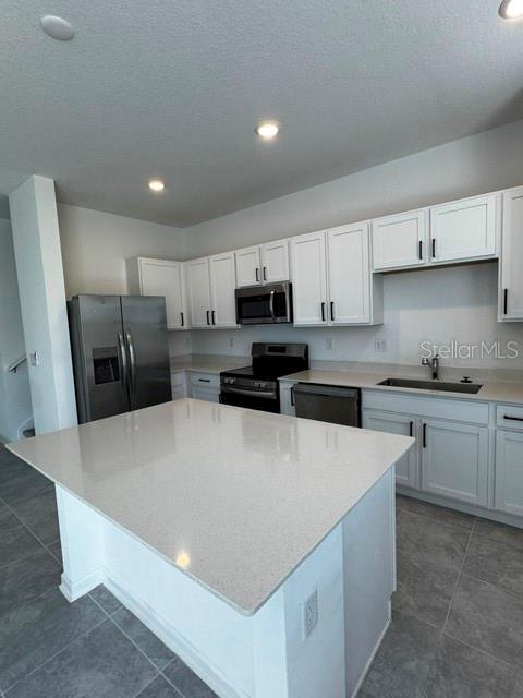 A modern kitchen features white cabinets, stainless steel appliances, and a large quartz-topped island — 2500 SKYLINE LOOP, KISSIMMEE, FL