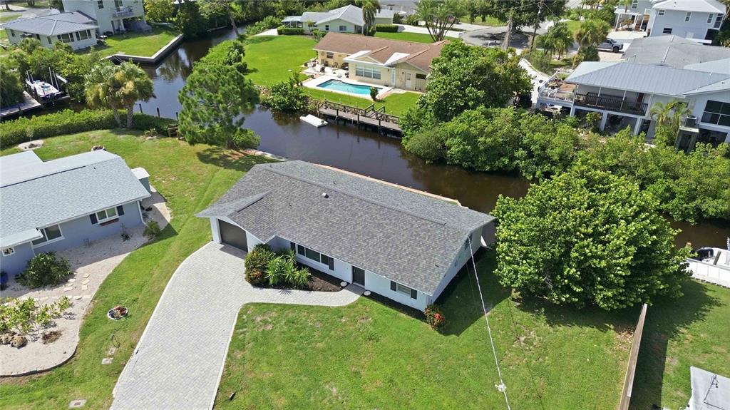 An aerial view shows a single-story house with a gray roof, driveway, and canal access — 706 QUAIL COURT, NOKOMIS, FL