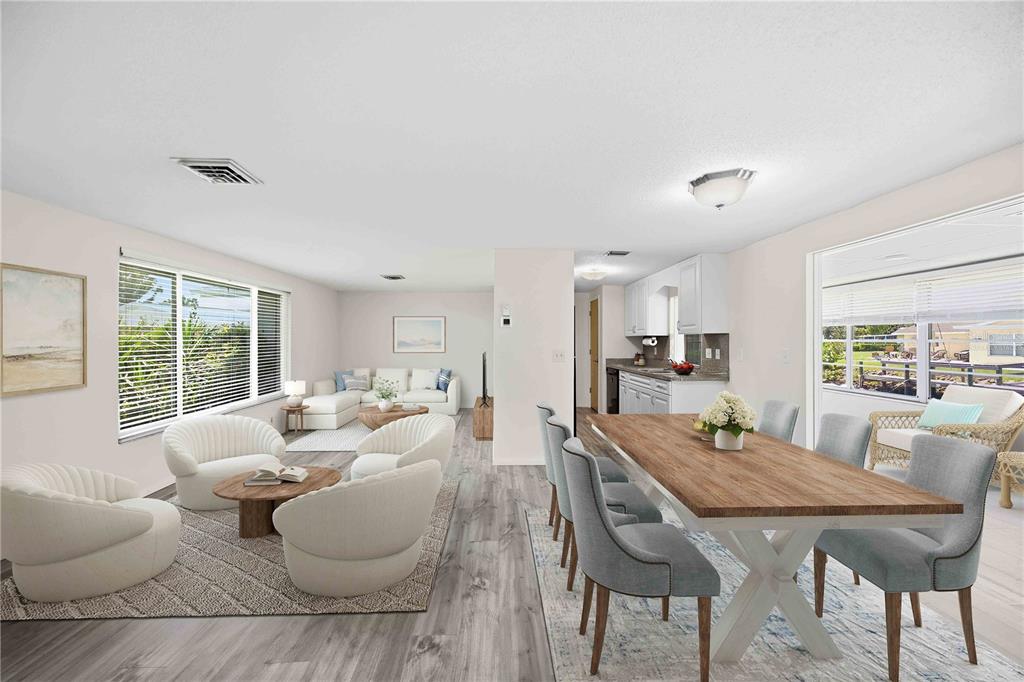 An open-concept living and dining area features light wood-look flooring, white walls, and modern furniture — 706 QUAIL COURT, NOKOMIS, FL