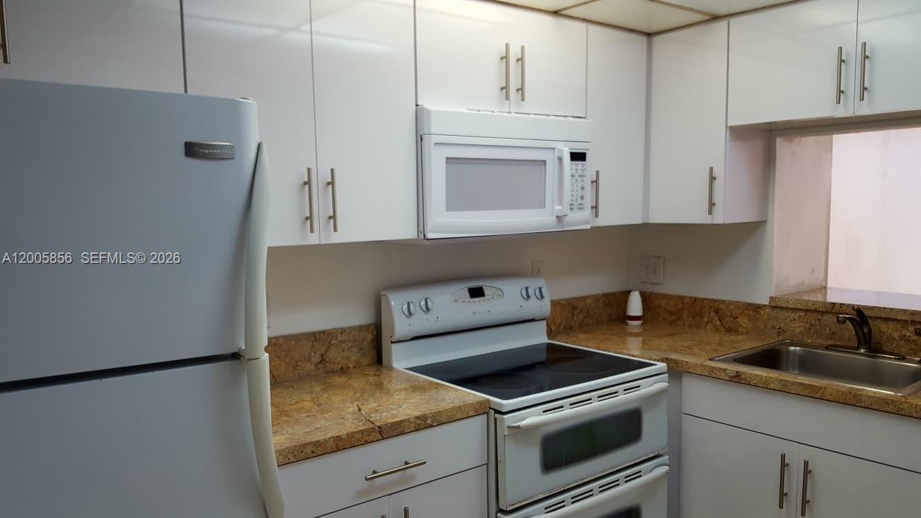 A kitchen features white cabinets, a white refrigerator, a white stove, and granite countertops — 19701 SW 114th Ave # 266, Miami FL 33157, MIAMI, FL