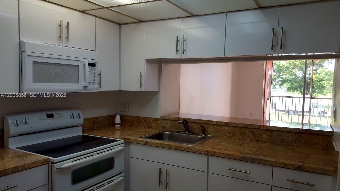 A kitchen with white cabinets, a microwave, a stove, and a window overlooking the outdoors — 19701 SW 114th Ave # 266, Miami FL 33157, MIAMI, FL