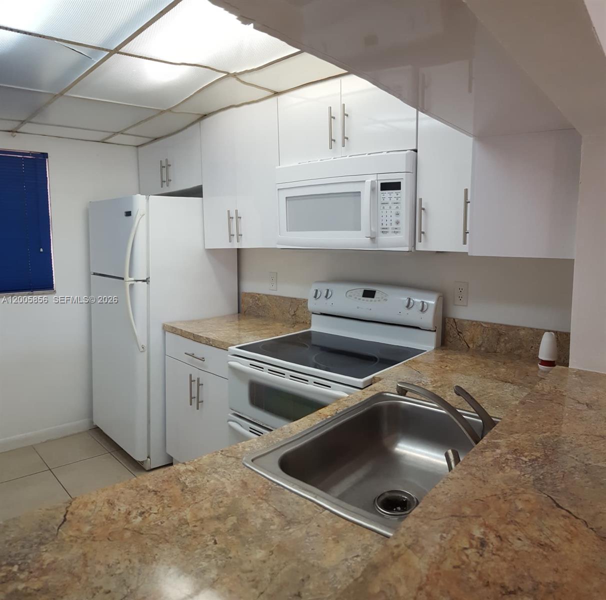 A kitchen features white cabinets, a white refrigerator, a white stove, and granite countertops — 19701 SW 114th Ave # 266, Miami FL 33157, MIAMI, FL
