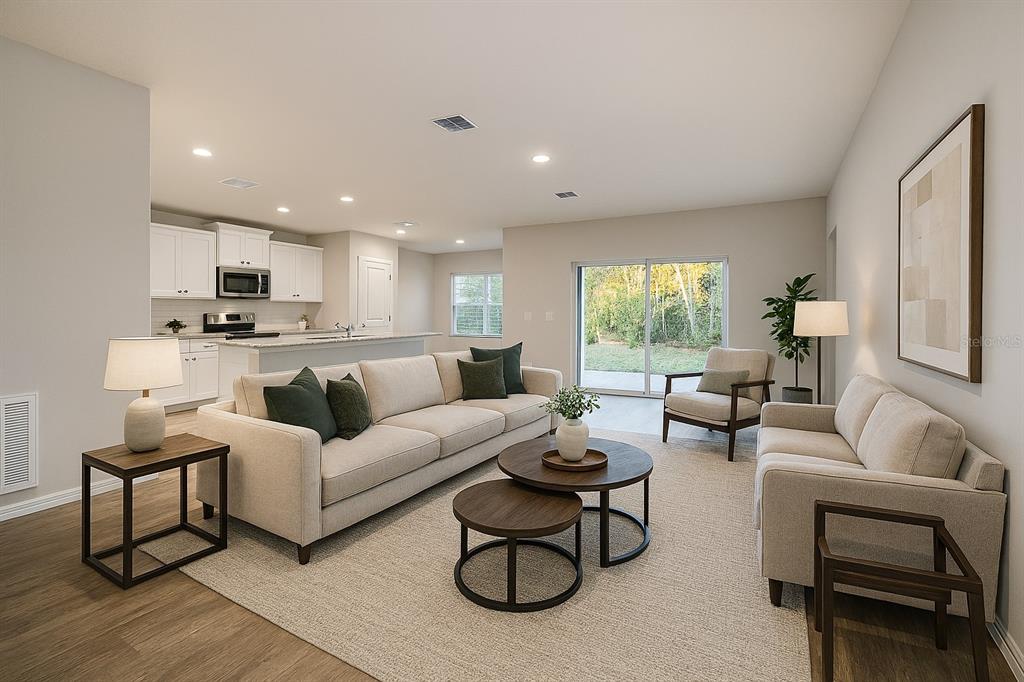 A living room with light-colored sofas, a round coffee table, and an open-concept kitchen — 63 REDWOOD ROAD, OCALA, FL