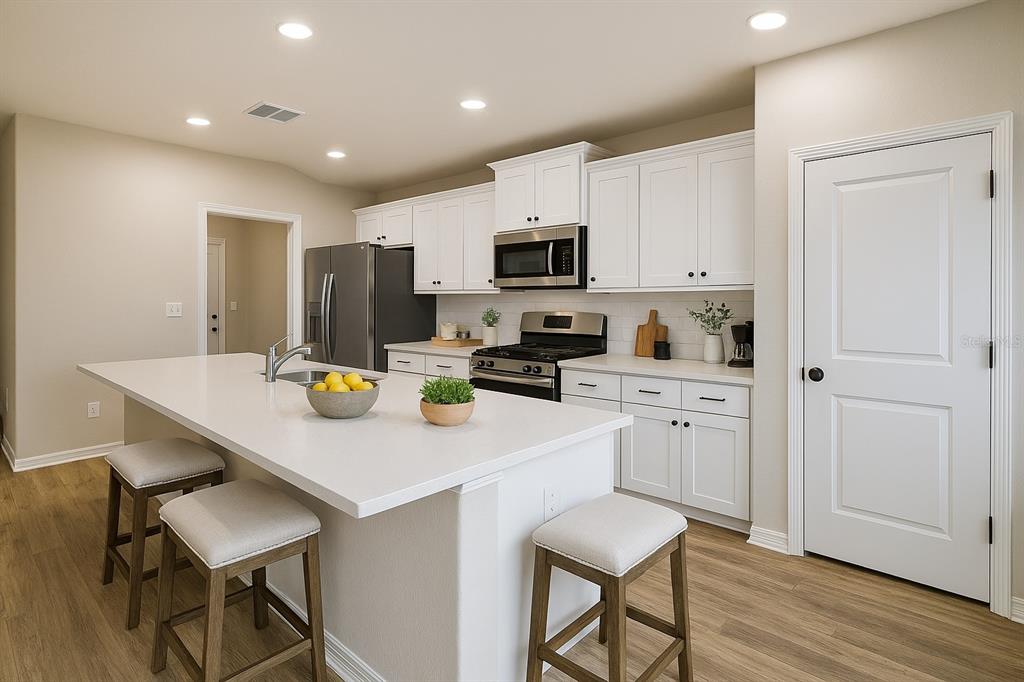 A modern kitchen features white cabinets, stainless steel appliances, and a large central island — 63 REDWOOD ROAD, OCALA, FL