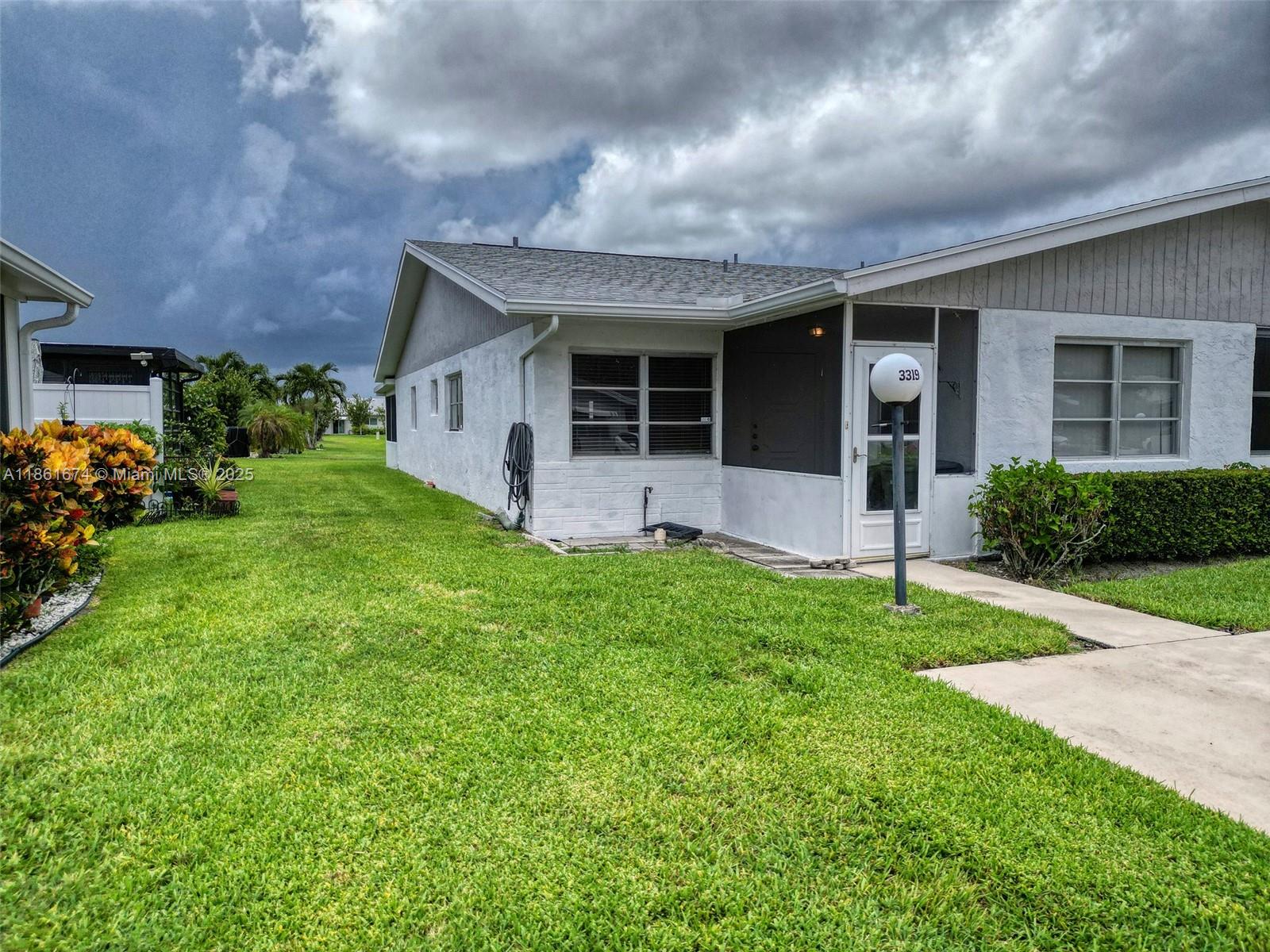 A white single-story house with a screened entryway and a lawn under a cloudy sky — 3319 Americo Dr, West Palm Beach FL 33417, WEST PALM BEACH, FL