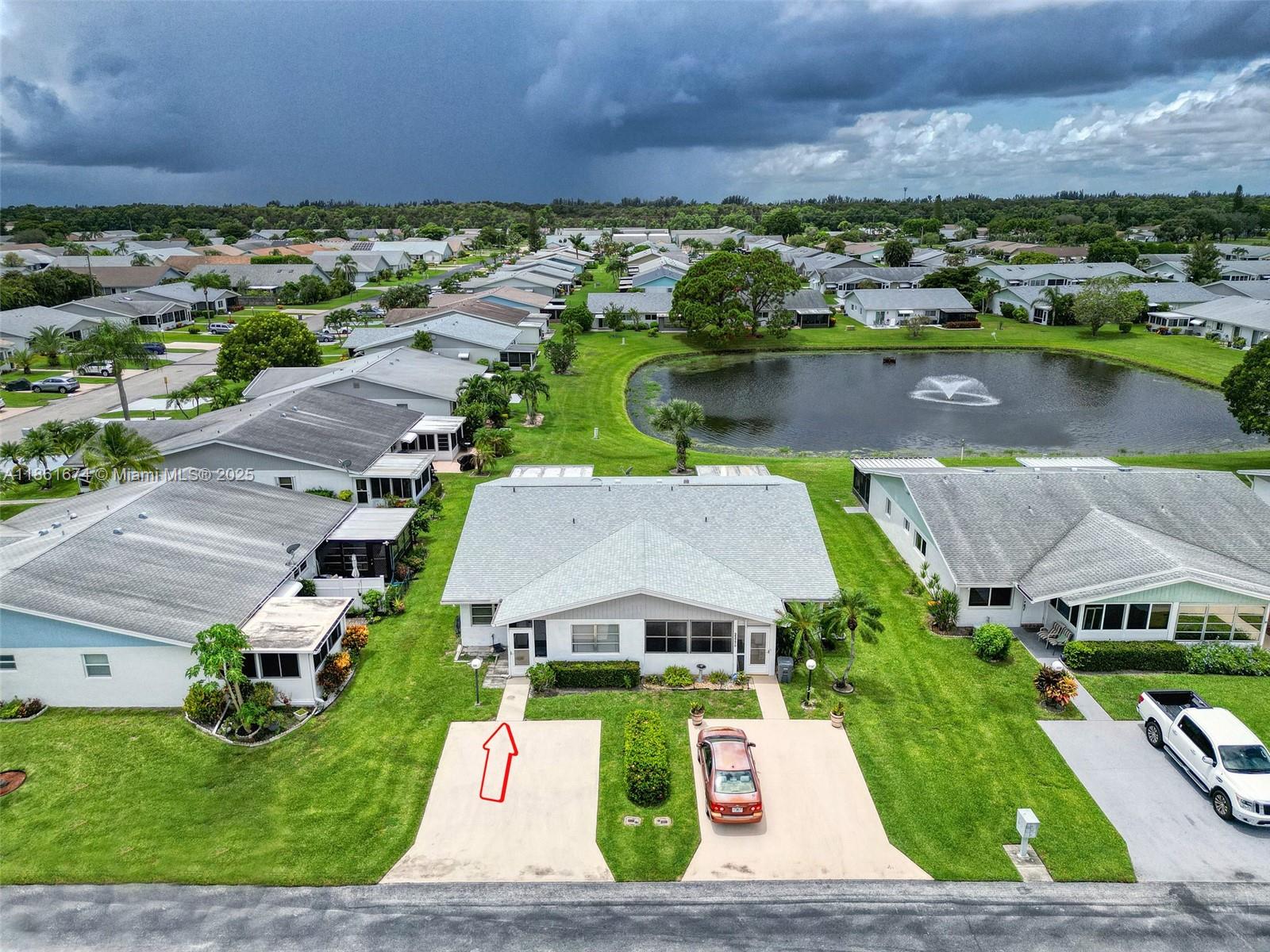 An aerial view shows a single-story duplex with two driveways and a pond behind it — 3319 Americo Dr, West Palm Beach FL 33417, WEST PALM BEACH, FL