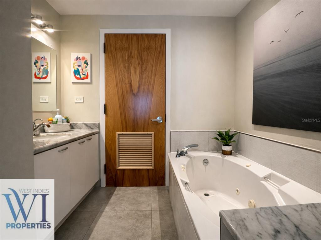 A bathroom features a wooden door, a white soaking tub, and a marble-topped vanity — 201 DORADO DEL MAR BLVD UNIT 2656, DORADO, PR